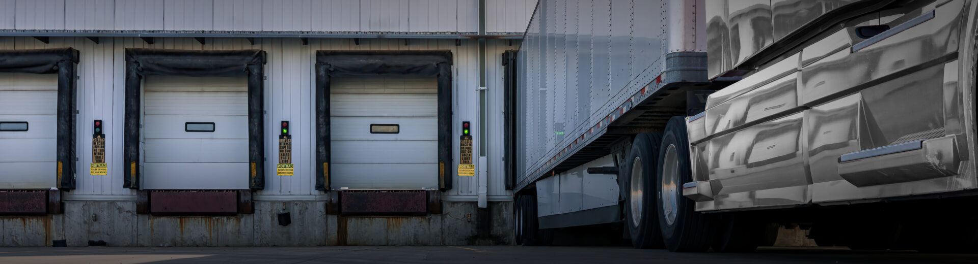 White truck and trailer parked in a loading dock 