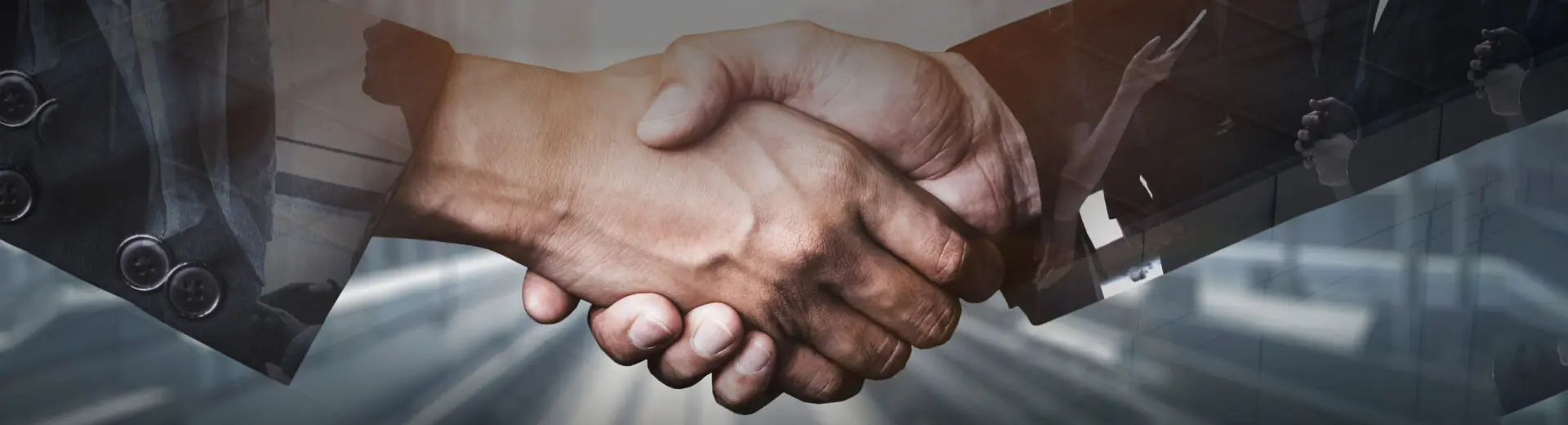 Business professionals shaking hands in front of window overlooking a road